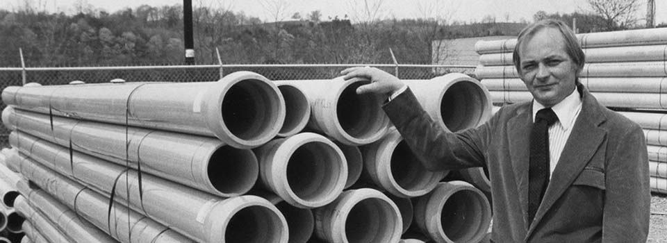 A Ferguson founder poses with piping to mark over 60 years of history in the plumbing supply business