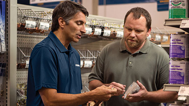 A Ferguson associate at an HVAC counter location discusses parts with a contractor.
