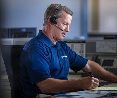 A Ferguson associate in a call center wears a phone headset and writes notes on a yellow legal pad.