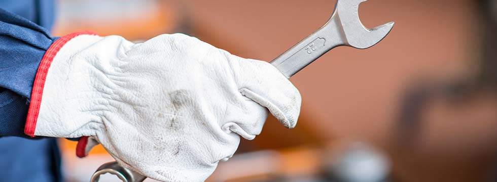 Worker with work glove holding wrench